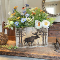 A wood moose box made with upcycled gray wood. A moose standing in the woods is wood-burned onto the front. It sits on a dining room table.  A wood moose box made with upcycled gray wood. A moose standing in the woods is wood-burned onto the front. It sits on a dining room table.